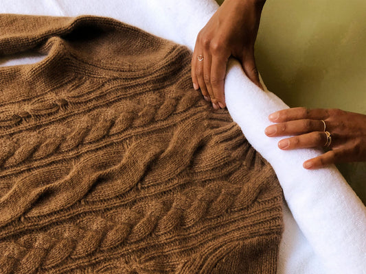 Rolling up a cashmere sweater in a clean white towel