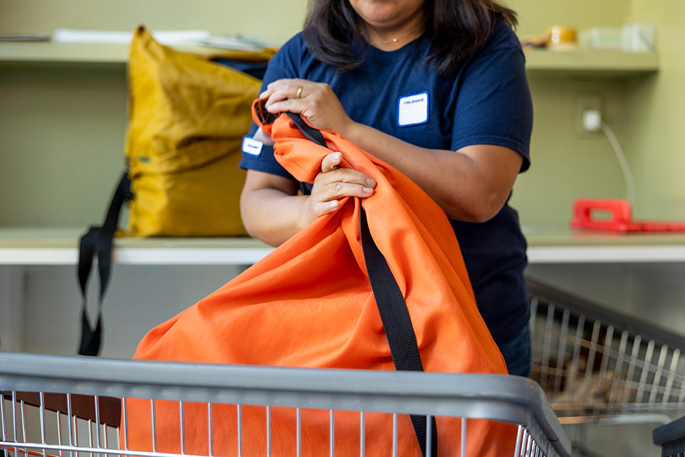 A woman in a navy t-shirt holding an orange laundry bag