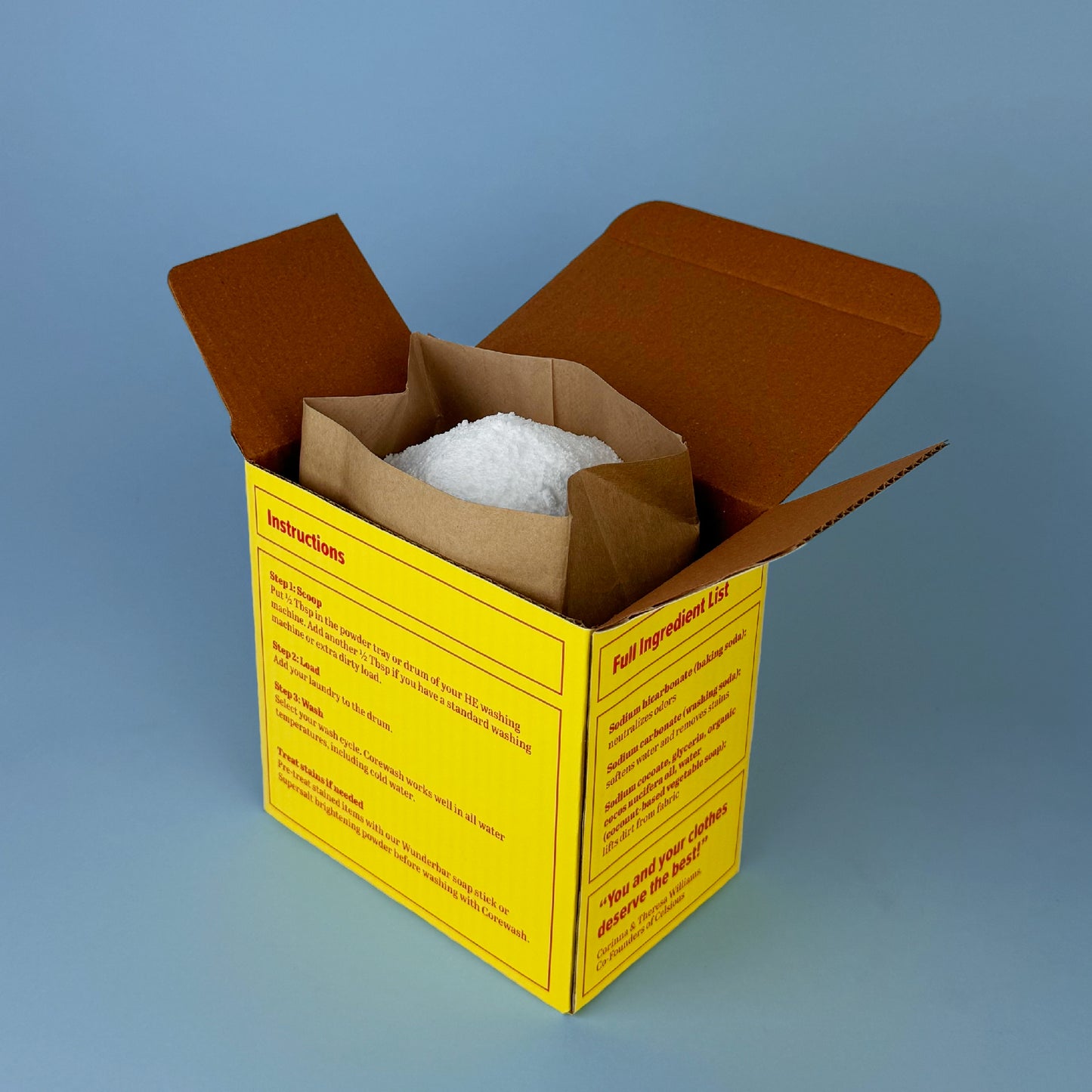 An open box of Corewash reveals a paper bag filled with white laundry powder