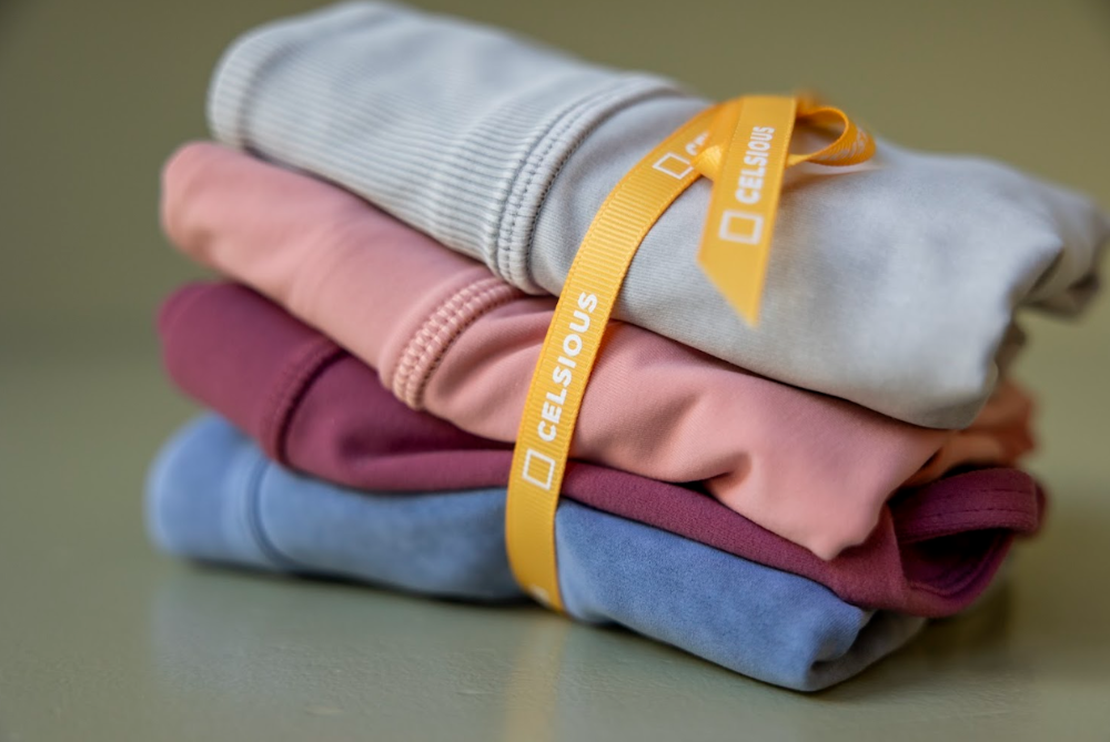 A neatly folded stack of sportswear tied with a yellow Celsious ribbon