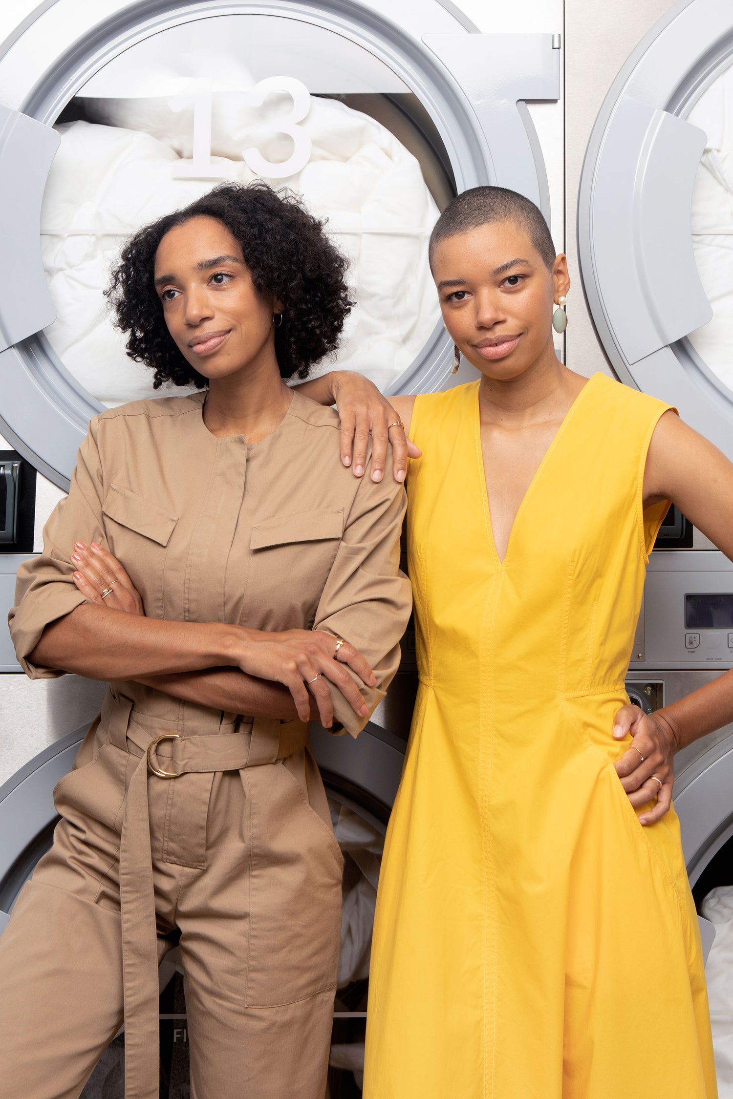 Corinna and Theresa Williams stylishly dressed in front of the dryers at their Brooklyn laundromat