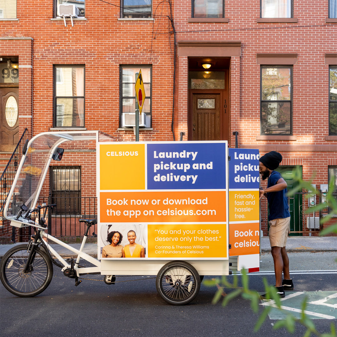 A smiling man opens the doors of a colorful laundry delivery e-bike