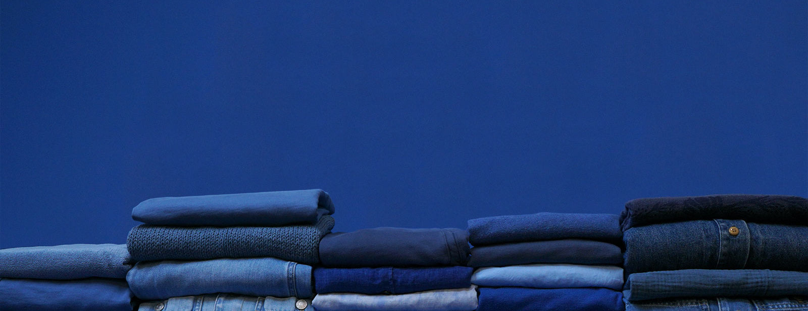 Neatly folded stacks of blue laundry in front of a blue backdrop at Celsious