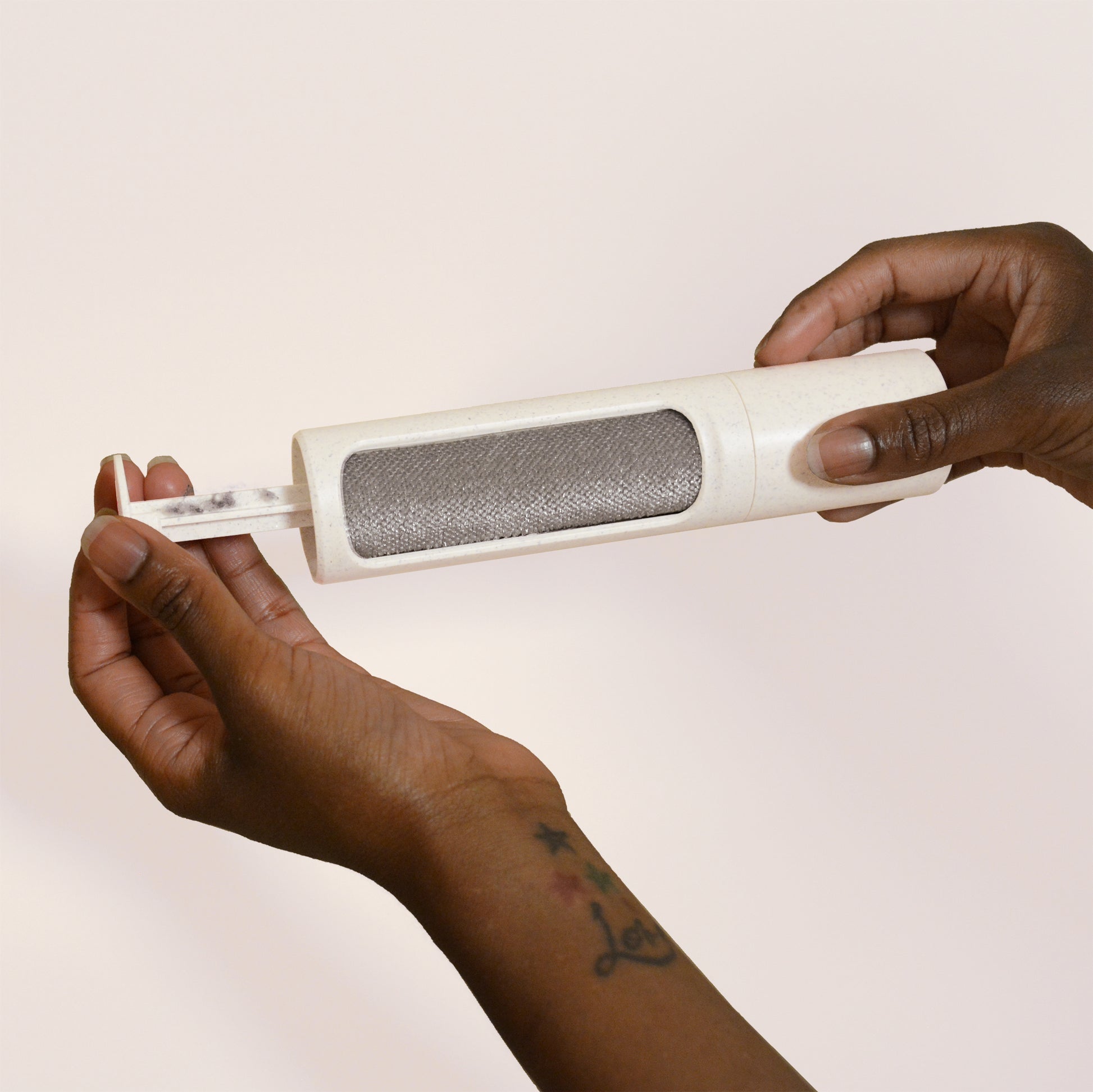 Opening the top of a beige reusable lint roller by Steamery to reveal the lint captured inside
