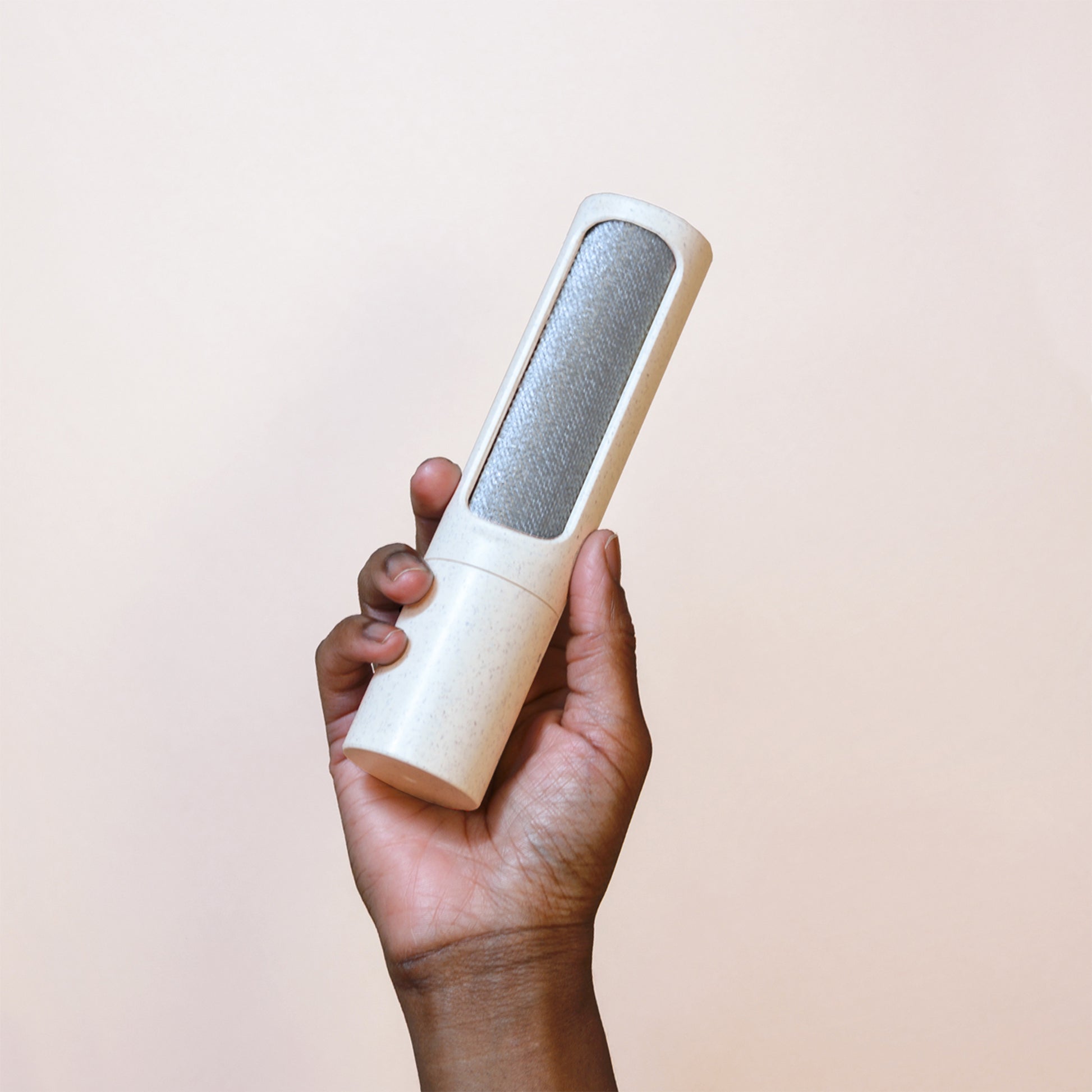 Holding up a beige reusable lint roller by Steamery