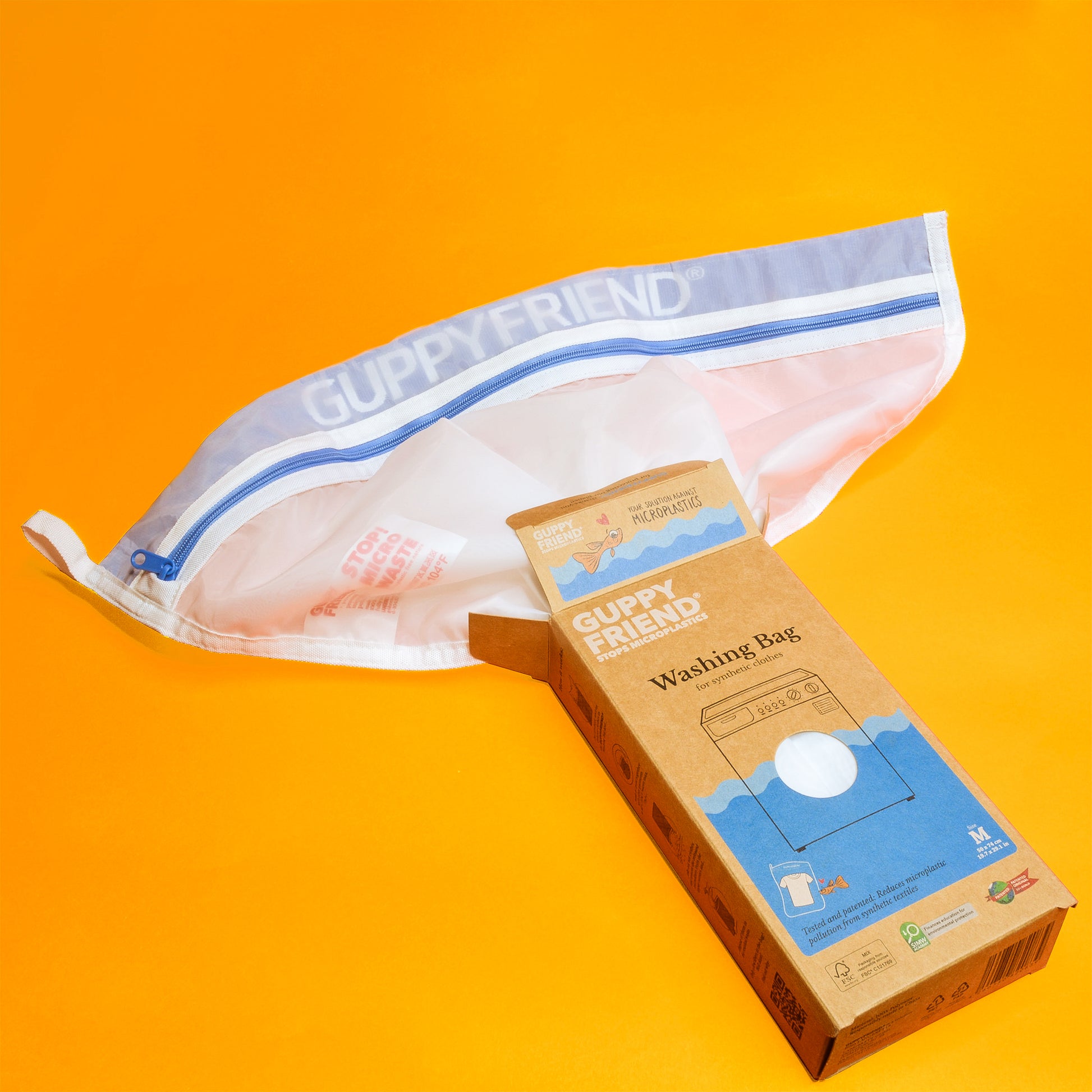 A Guppyfriend microfiber laundry bag peeks out of kraft paper packaging