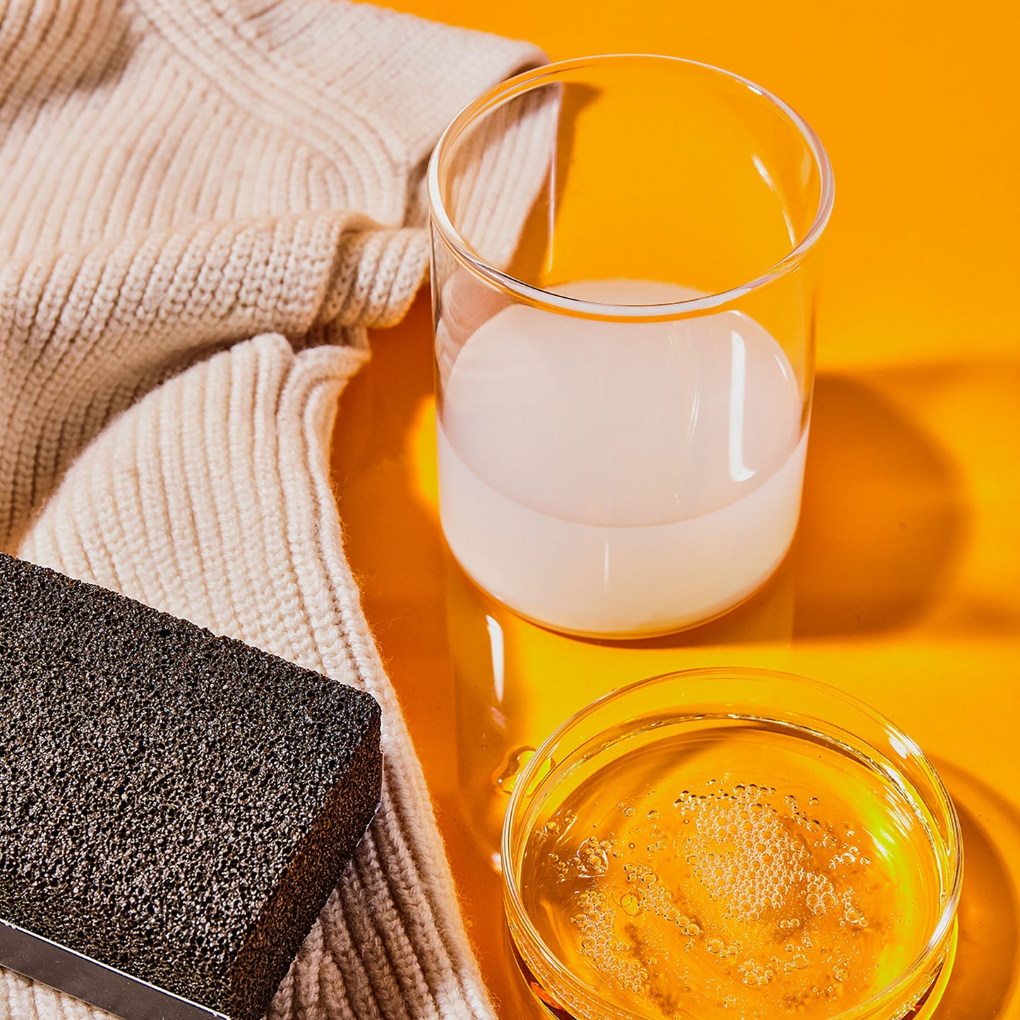A sweater stone, wool detergent and conditioner, and a knit sweater