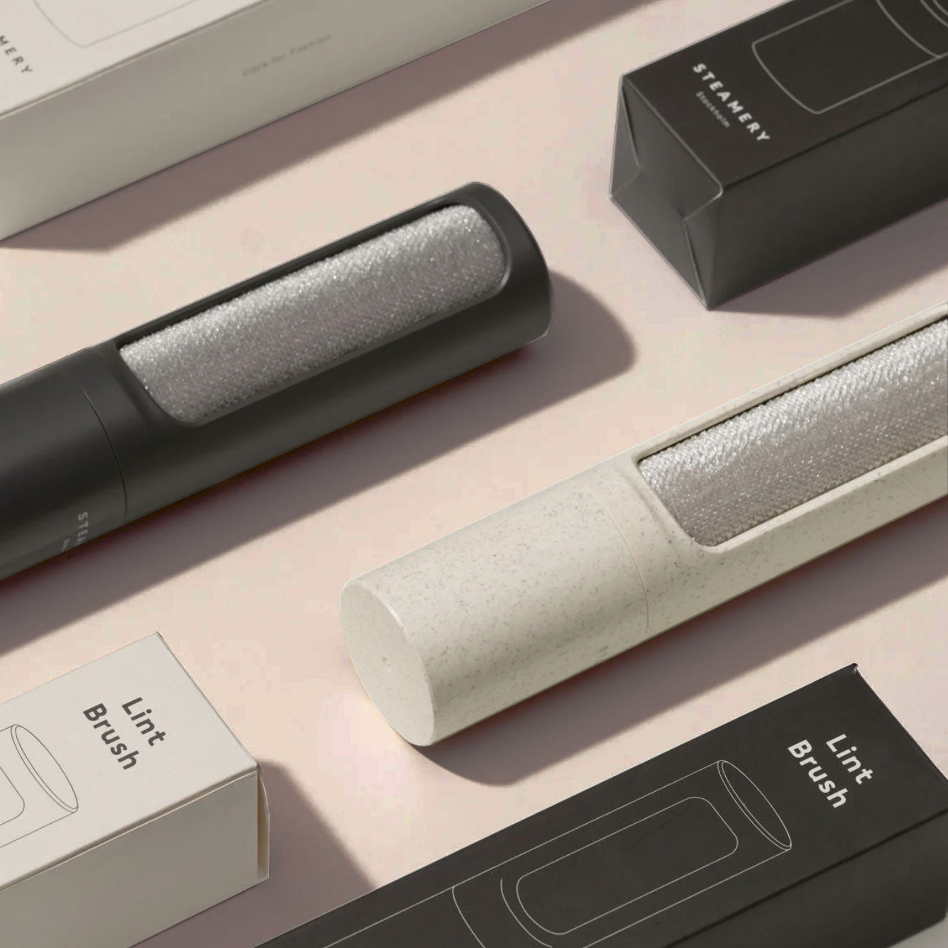 Steamery's sleek lint removing devices in sand and charcoal in neat rows with packaging
