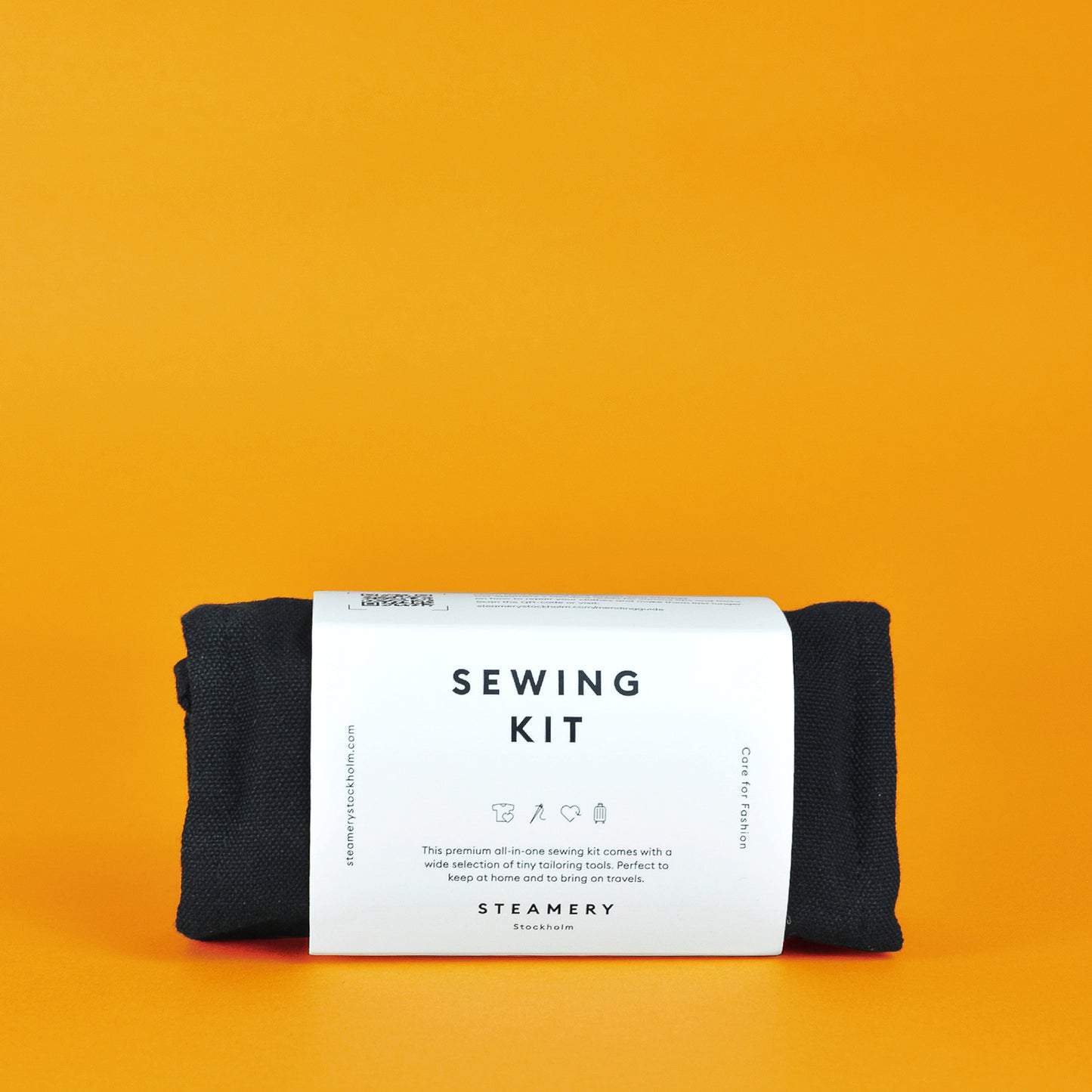 A rolled up Steamery sewing kit in a white paper sleeve