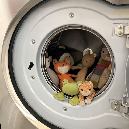 A front loading washer filled with adorable stuffed animals that look to be peering out of the washer