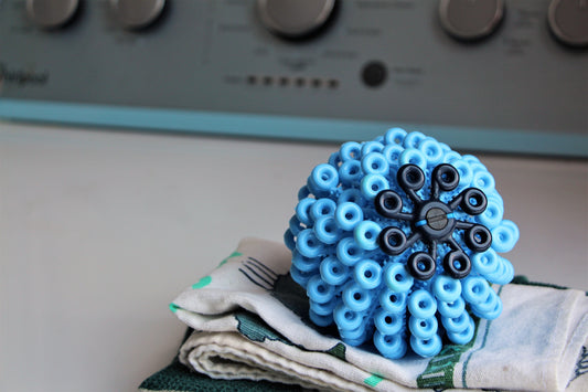 The Cora Ball, a microfiber catching laundry ball, on a stack of dish towels
