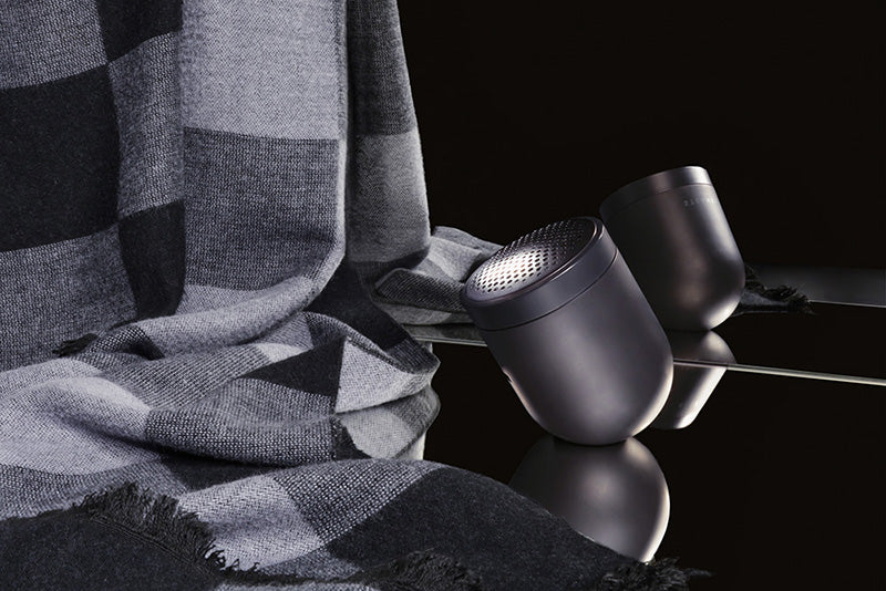 A sleek dome shaped fabric shaver displayed with a checkered men's scarf