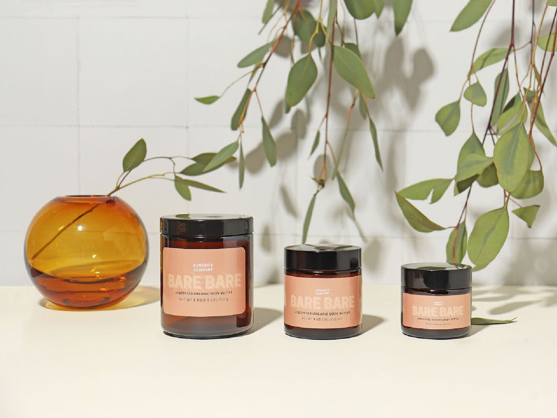 Jars of Runako body butter and eucalyptus branches