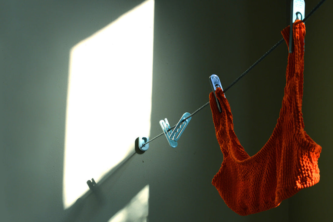 An orange swim top hangs from a clothesline