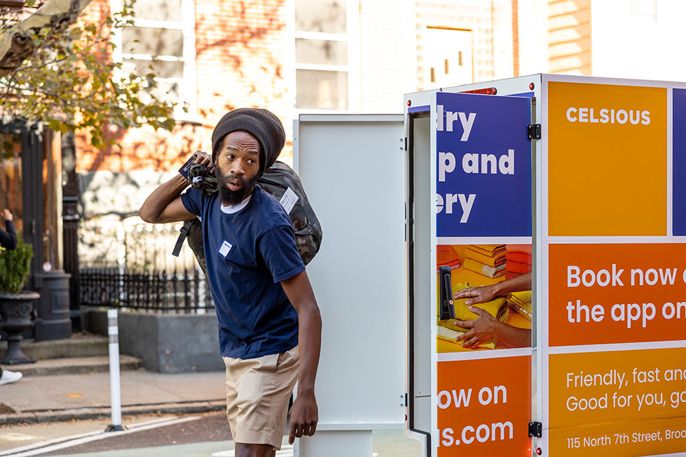 A man wearing a navy t-shirt carries a bag of laundry over his shoulder