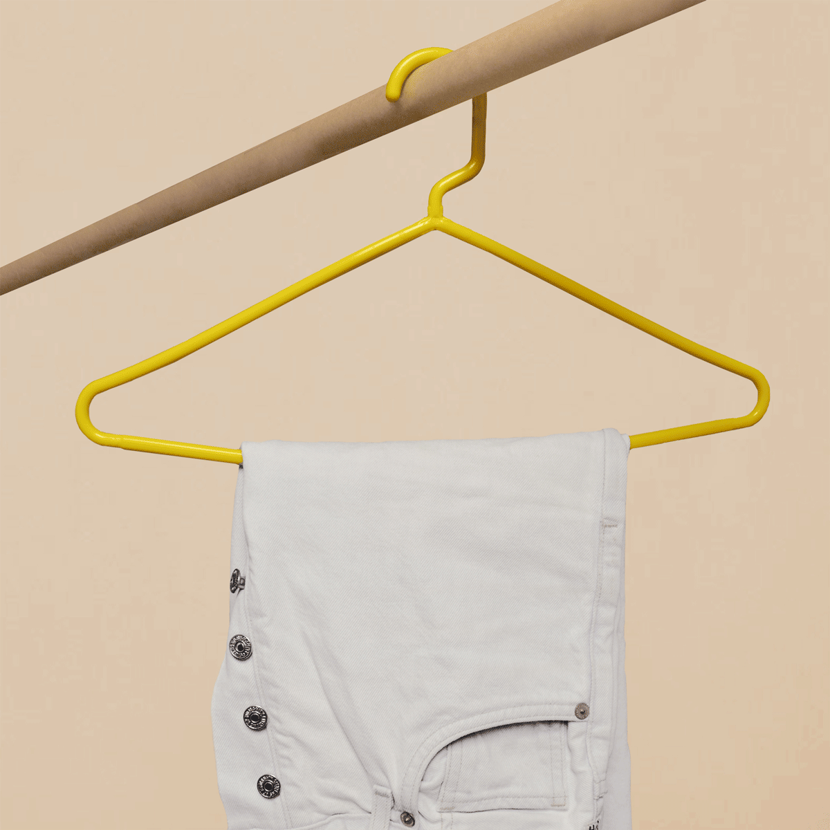 A gif of a high quality yellow hanger replacing a low quality hanger bending under the weight of jeans