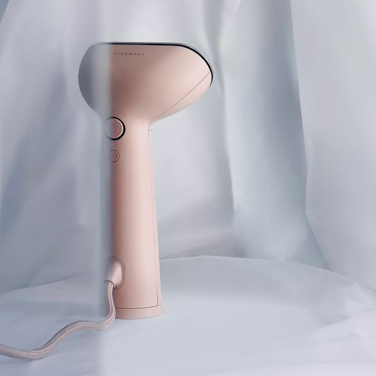 A sleek iron steamer in a rosy pink shade draped with soft fabric