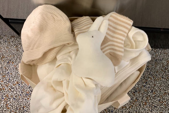 A basket of baby clothes and a plush rabbit ready to be washed at Celsious