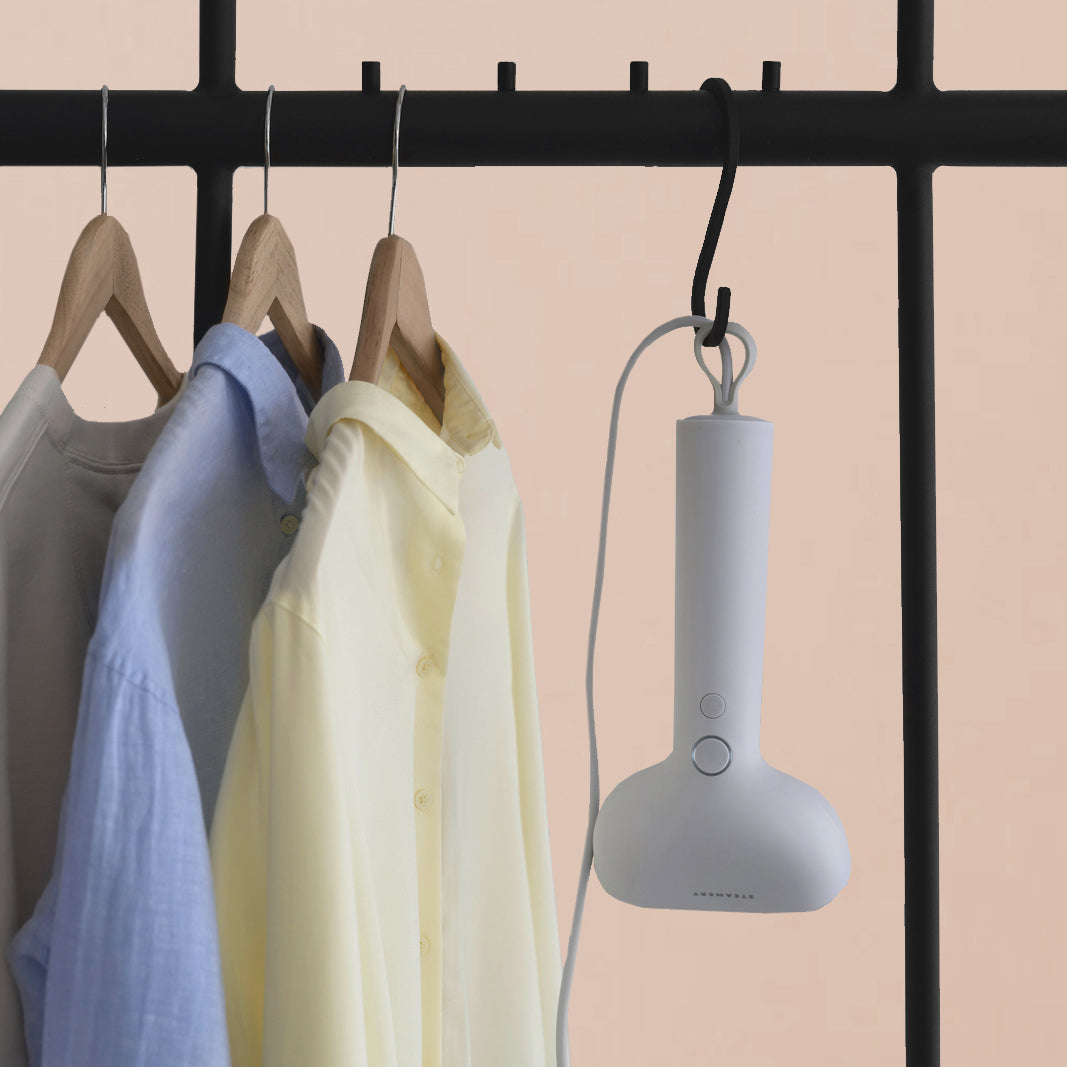 A white Cirrus X steamer hangs upside down from a garment rack