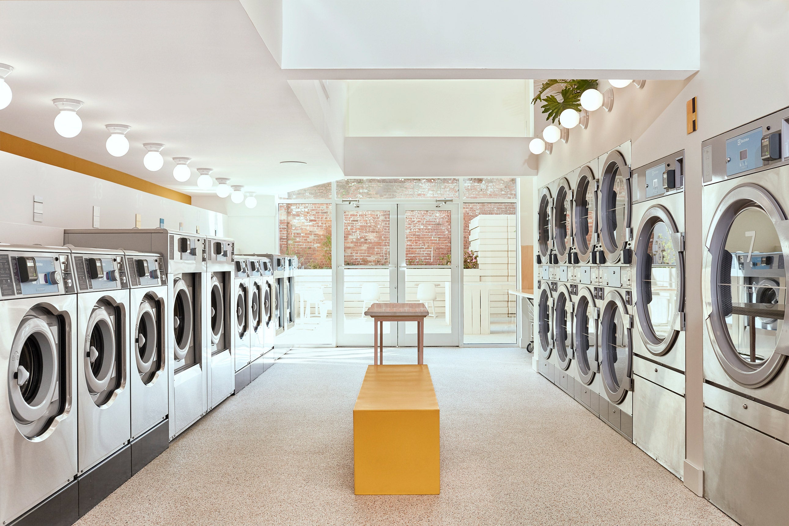 The light-filled interior at Celsious laundromat features yellow accents