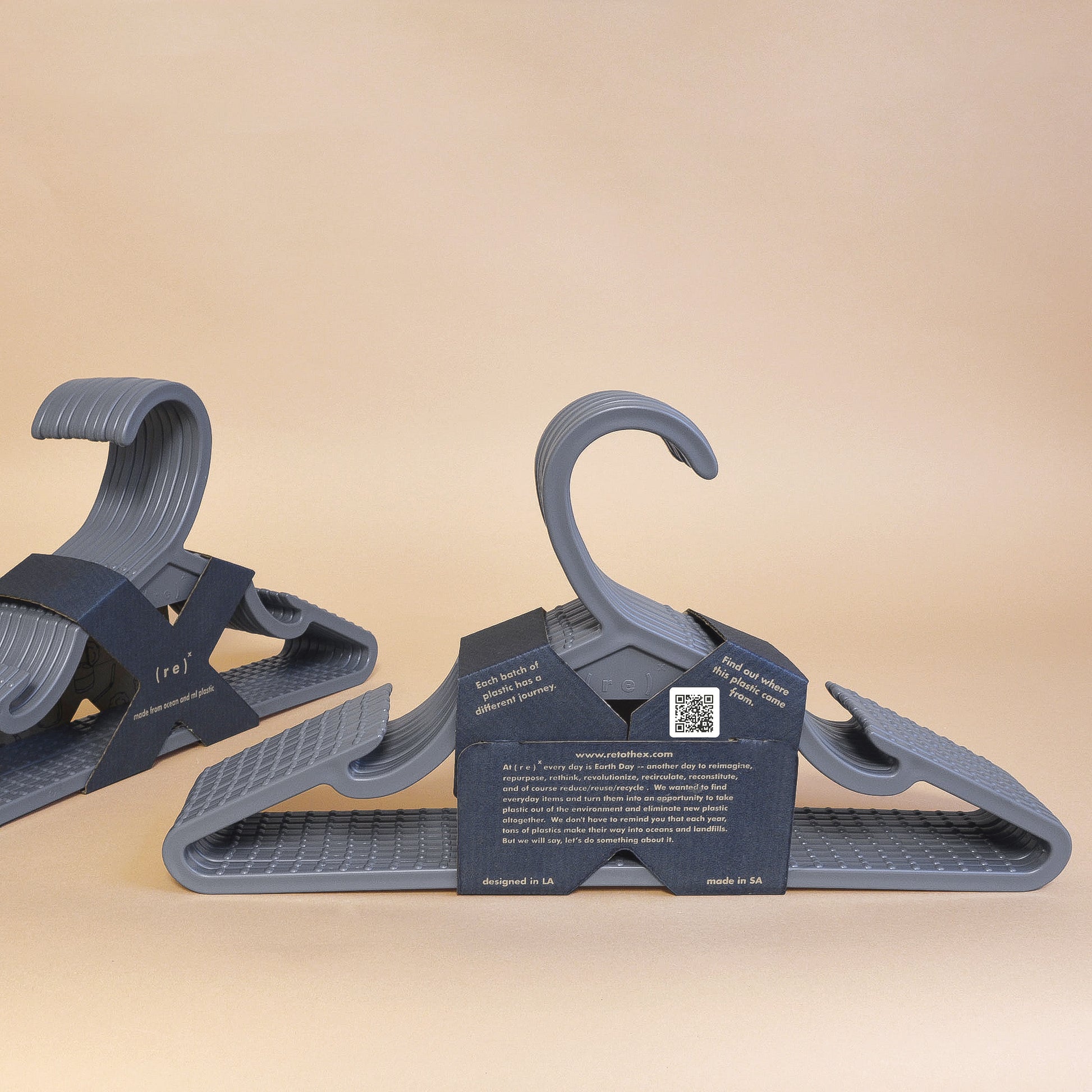 Two grey 10-packs of recycled ocean plastic hangers with anti-slip grooves held together by a cardboard label with a QR code on the back