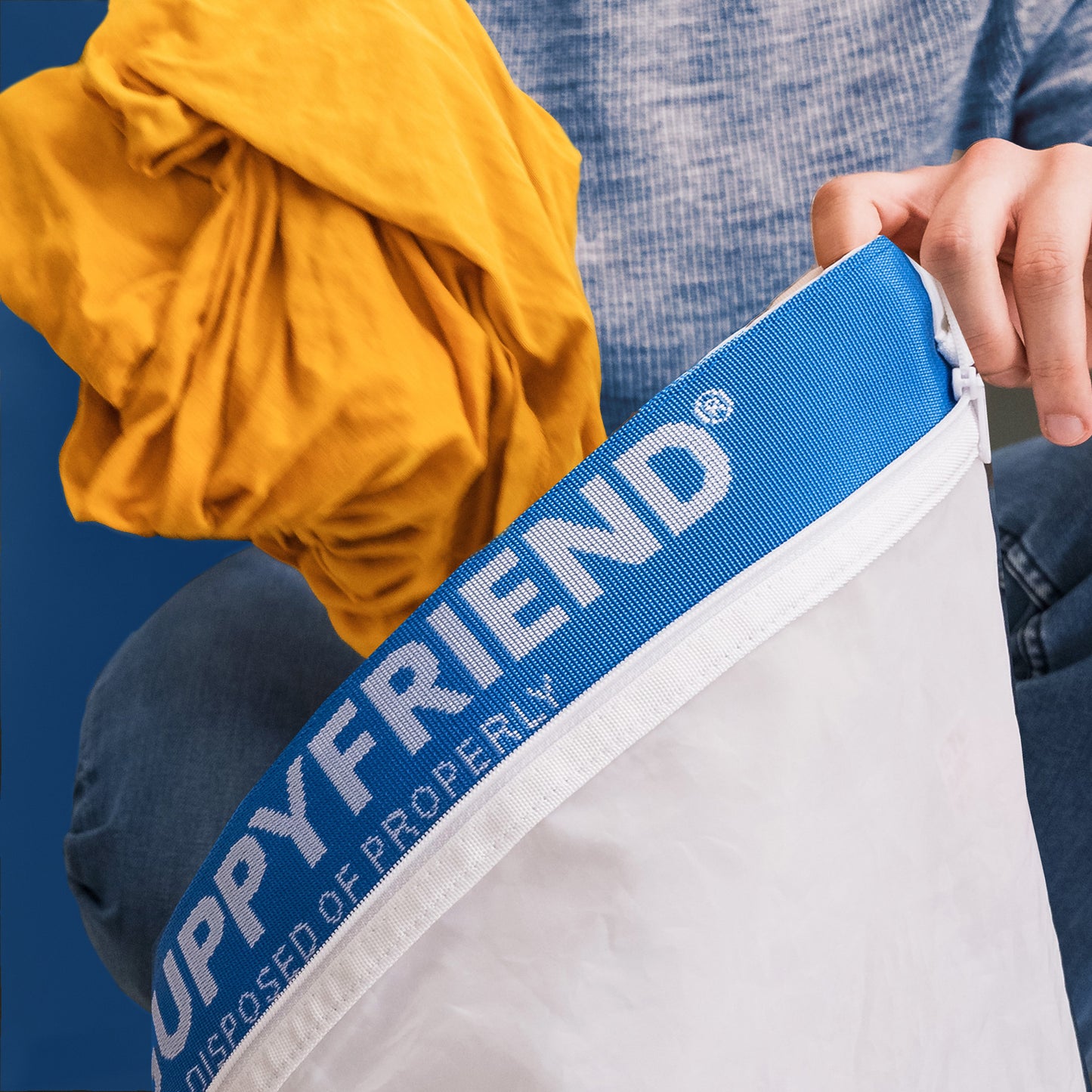 A man puts a balled up yellow shirt into a Guppyfriend laundry bag to capture microfibers shed in the wash