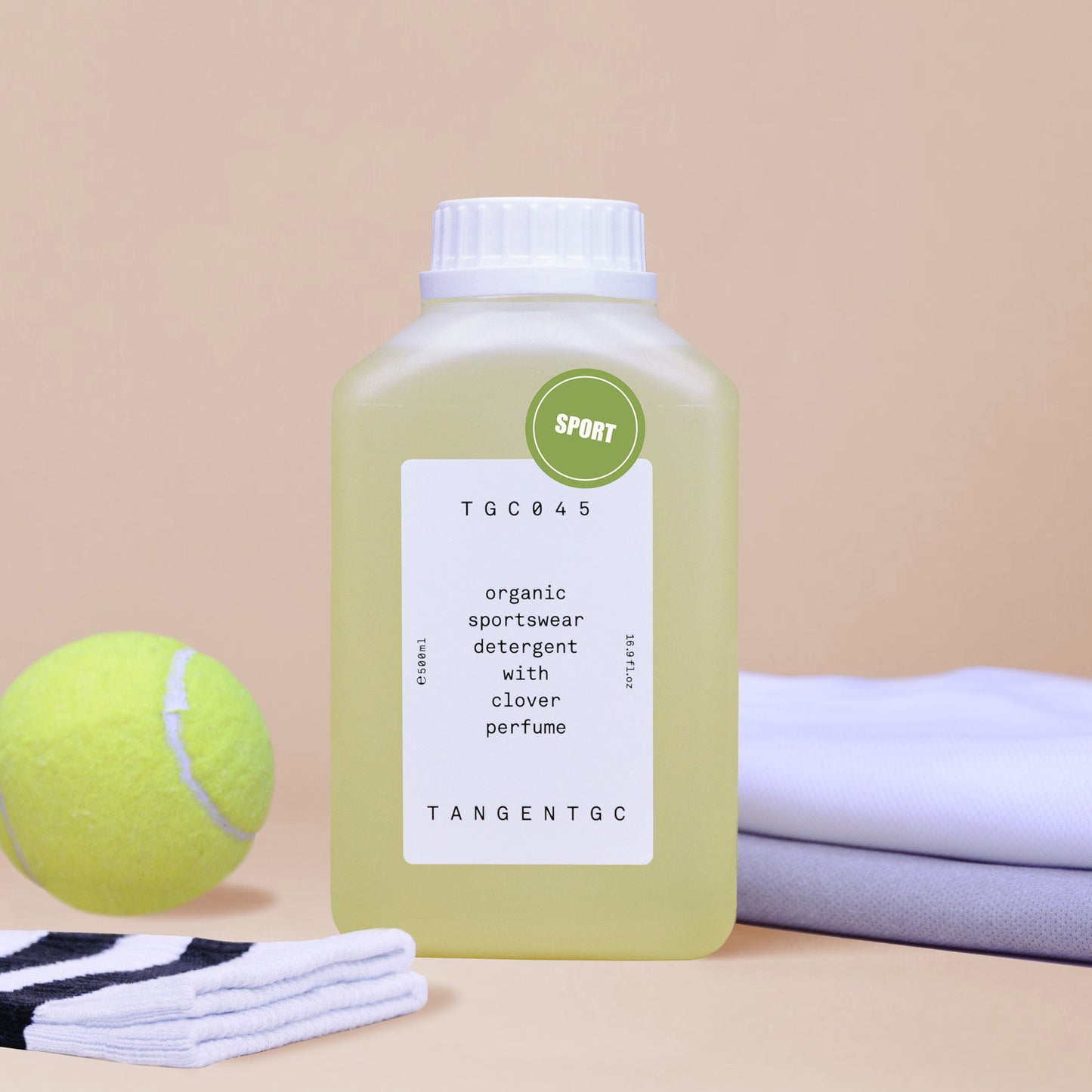 A rectangular bottle of sportswear detergent shot with tube socks, neatly folded t-shirts and a tennis ball