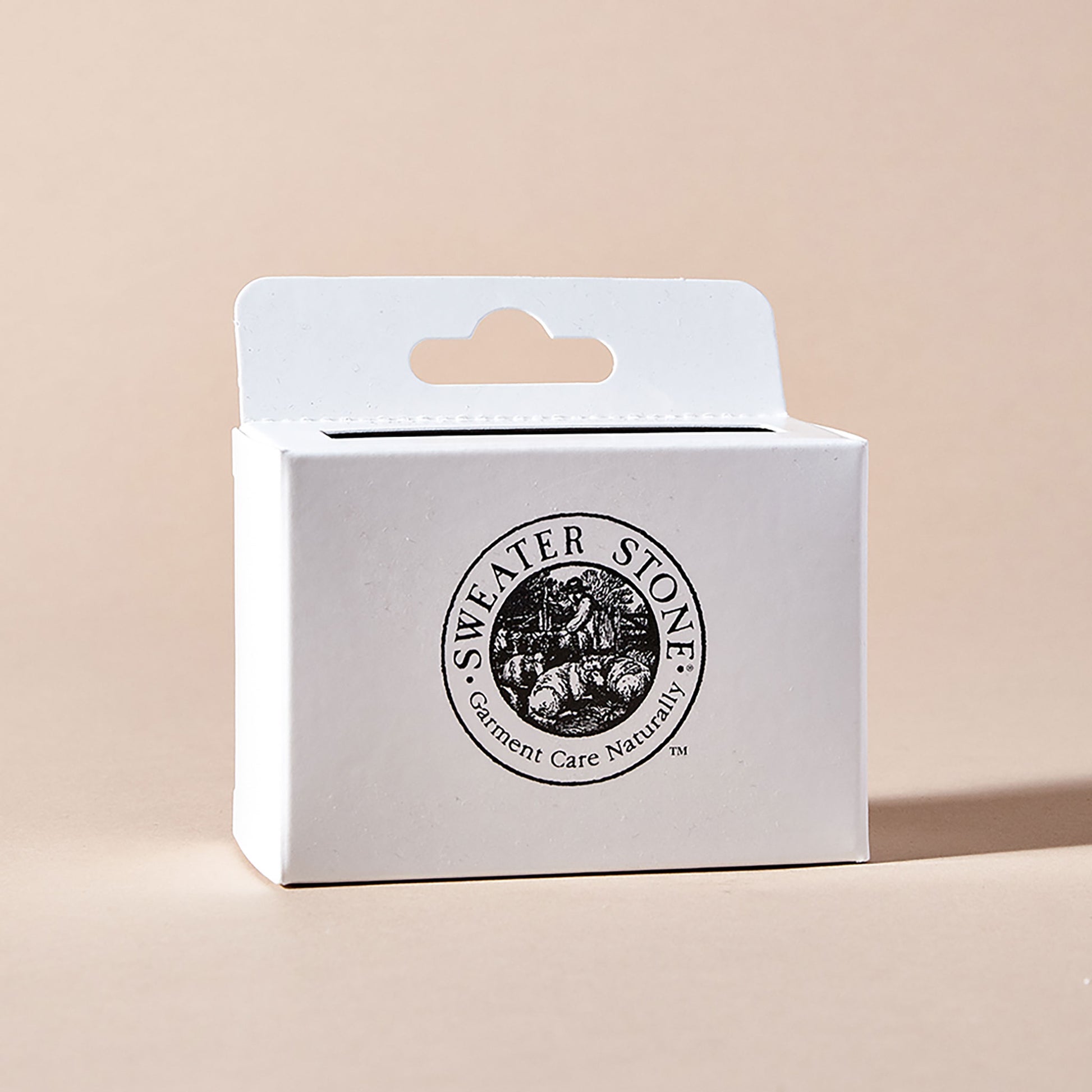 The front of a white rectangular box with the words "sweater stone - garment care naturally"