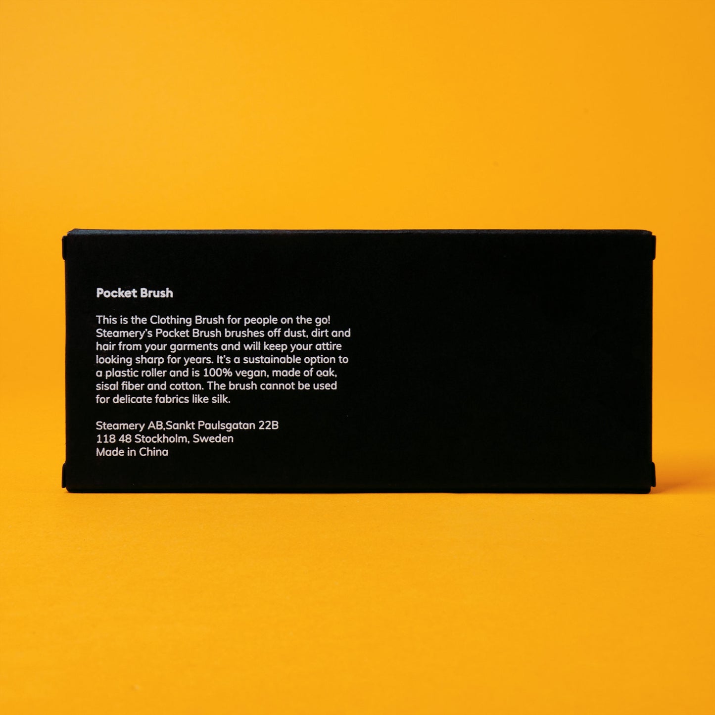 The back of the black paper packaging for Steamery's pocket brush; there is a description of the product with a Swedish address underneath