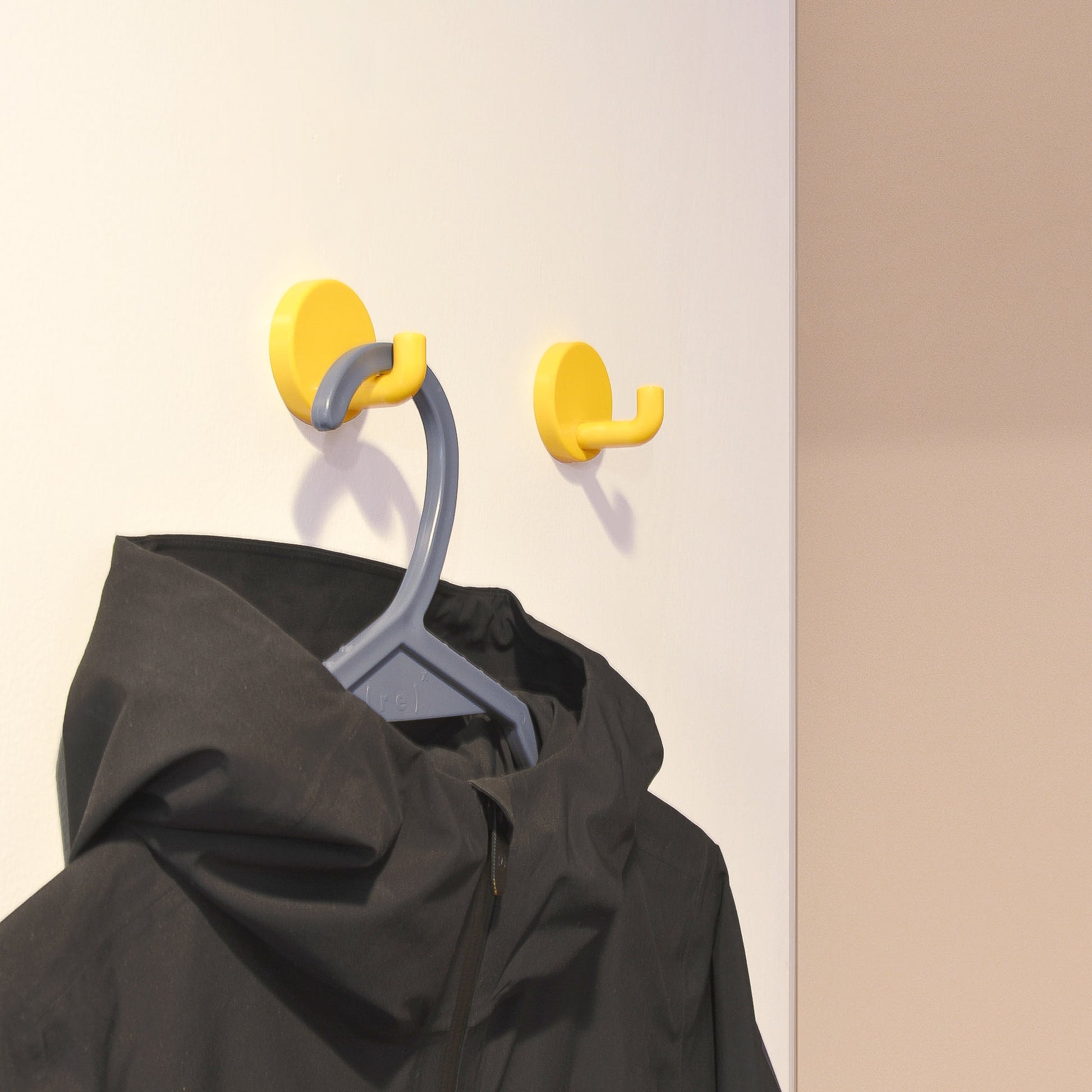 A black winter jacket hangs from a grey recycled ocean plastic hanger