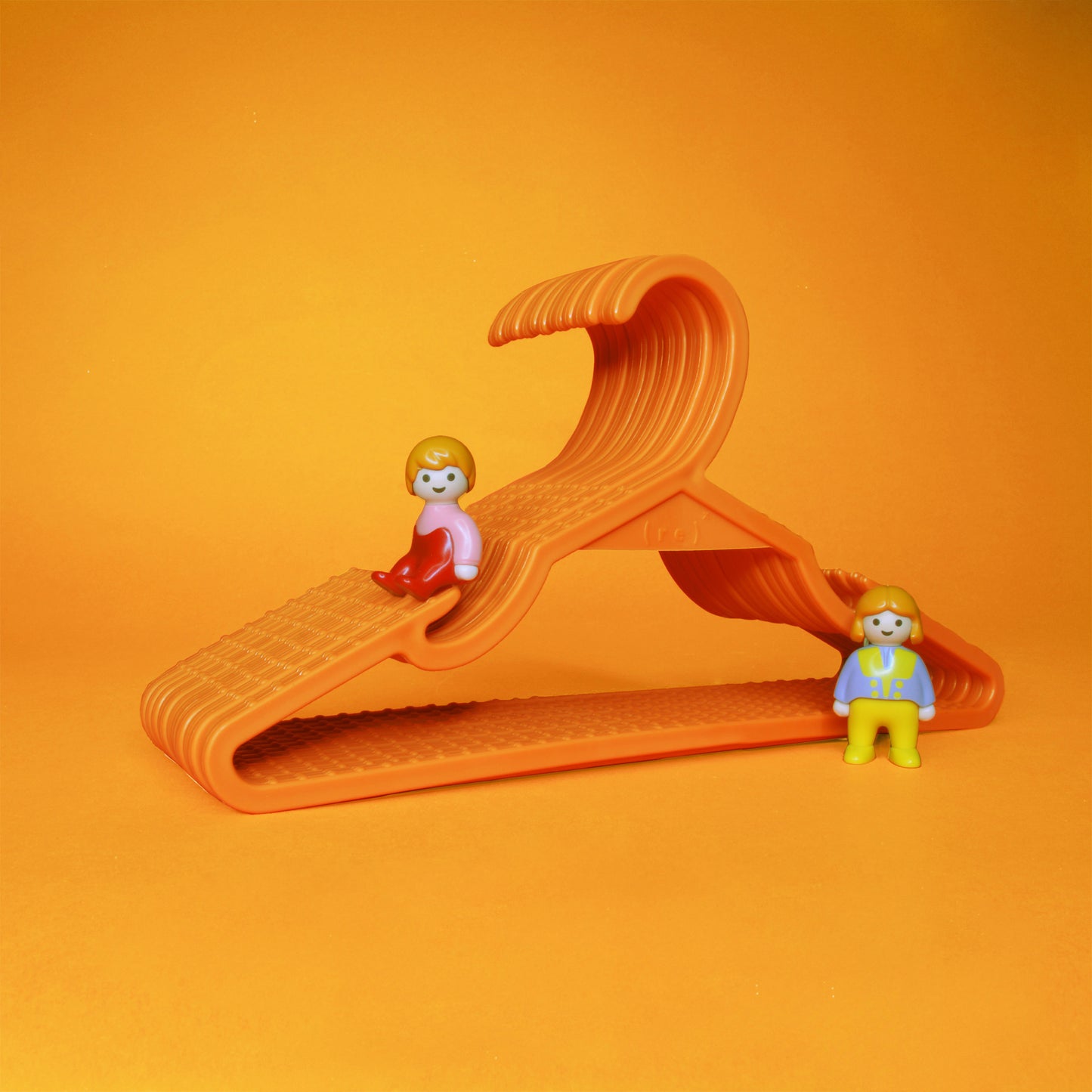 A set of orange kids hangers and two little toy figurines perched on the set