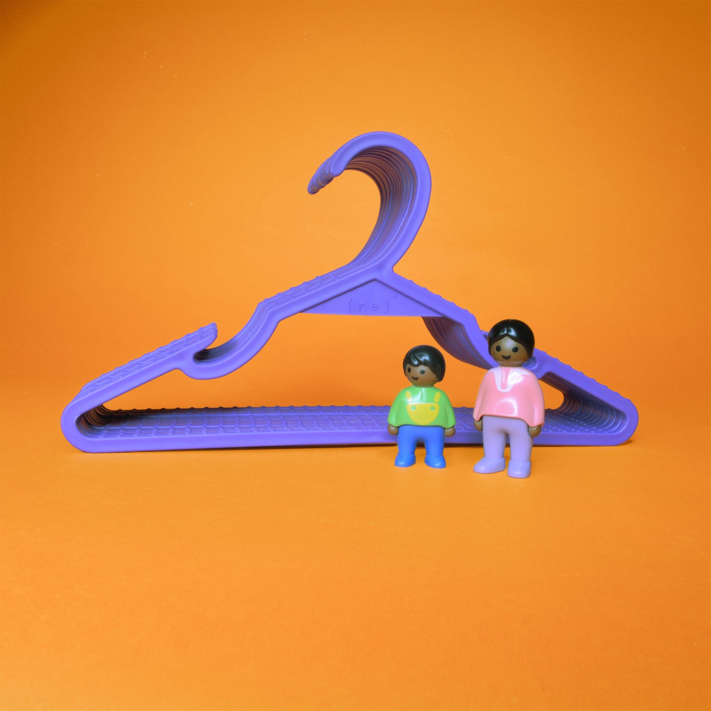 A set of purple kids hangers and two little toy figurines of a mother and child placed in front of the set
