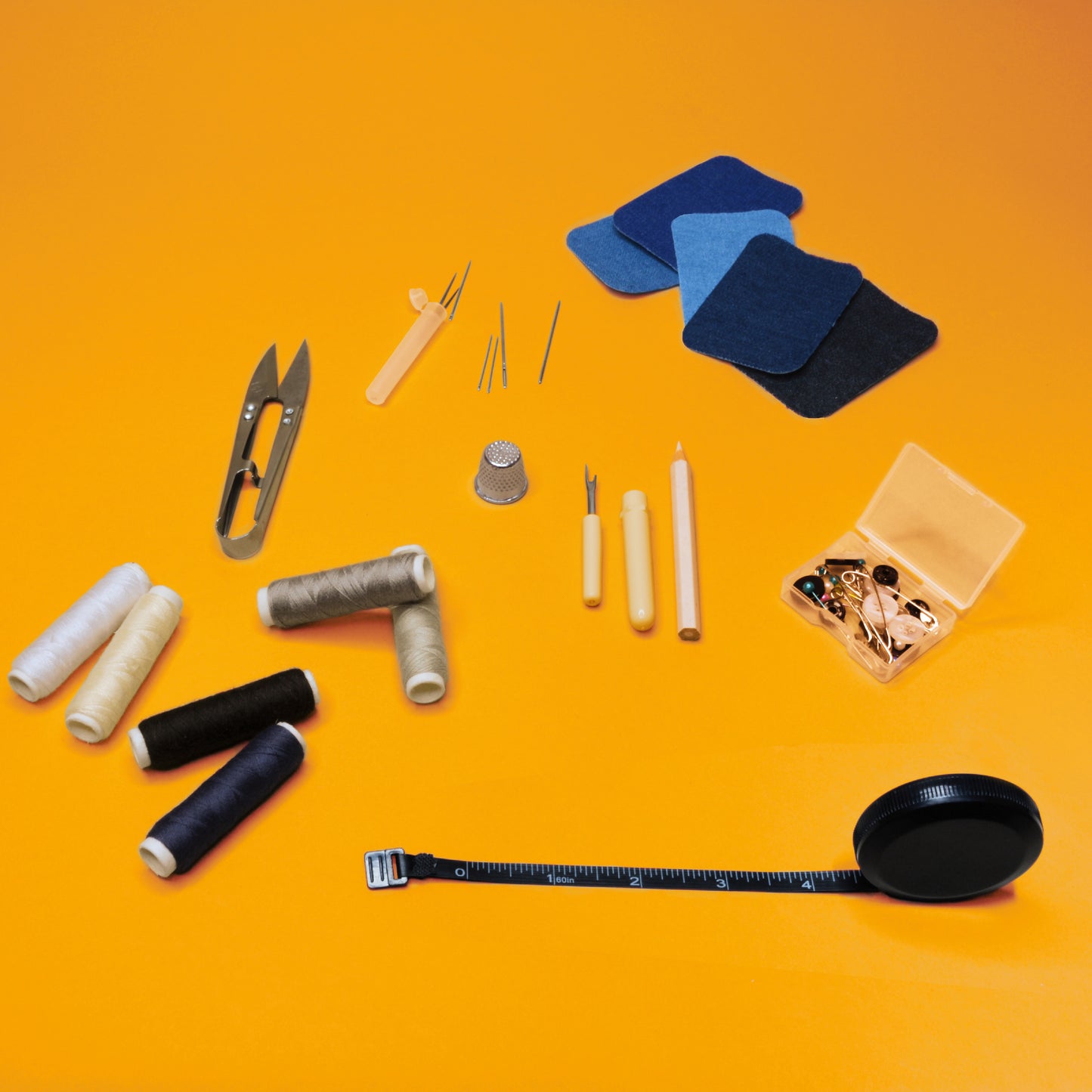 The contents of the Steamery sewing kit: thread scissors, sewing needles, fabric patches, six spools of thread, a seam ripper, a tape measure, a thimble, safety pins and buttons